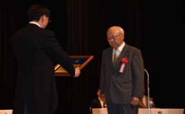 写真：一般表彰者を代表して表彰状を受け取る 弥生っこ村民会後藤欣二さん
